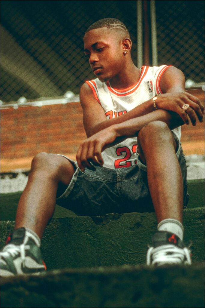 Young athlete in Chicago Bulls jersey sitting outdoors in contemplation.